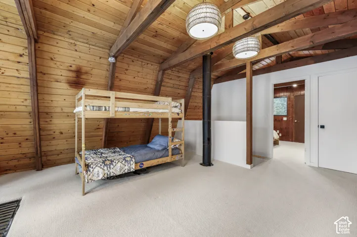 Vaulted wood-paneled ceilings with exposed wood beams, wall-to-wall carpeting, and contemporary pendant lighting fixtures