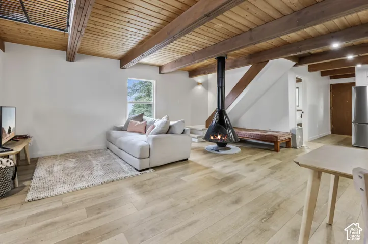 Vaulted wood-paneled ceiling with exposed beams, wood-finish flooring, a contemporary suspended fireplace, and a window providing natural light