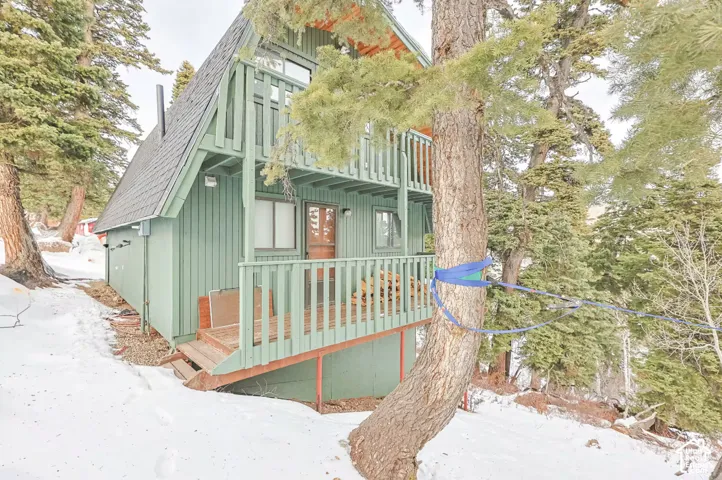 A-frame architecture with vertical siding, a covered entry, and an upper balcony