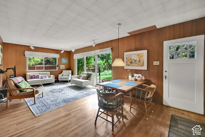 Wood-finish flooring throughout, wood paneling, sliding glass door, white paneled door with glass inserts, and track lighting