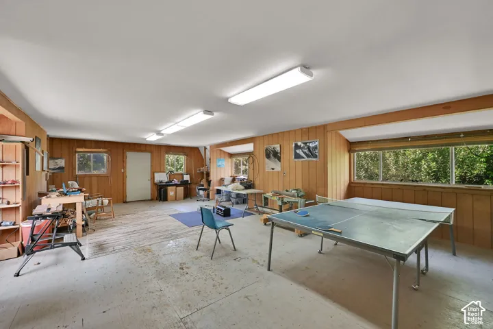 Spacious room featuring wood-paneled walls, multiple windows, and overhead fluorescent lighting