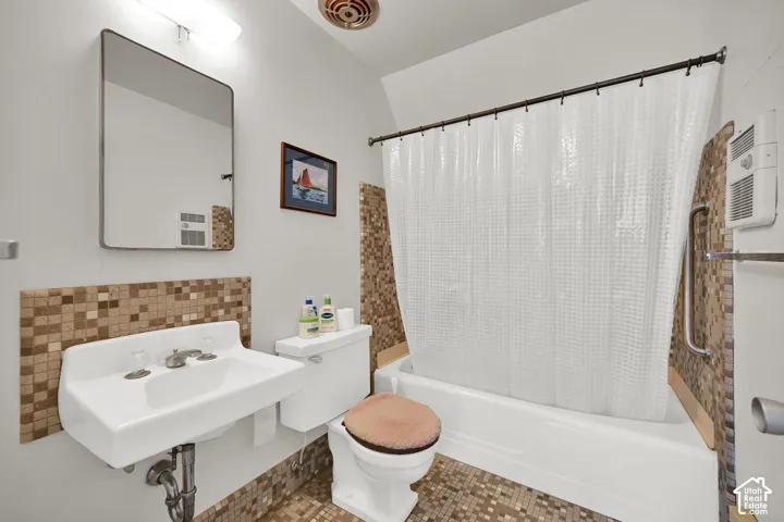 White wall-mounted sink, ceramic toilet, and white bathtub with shower rod