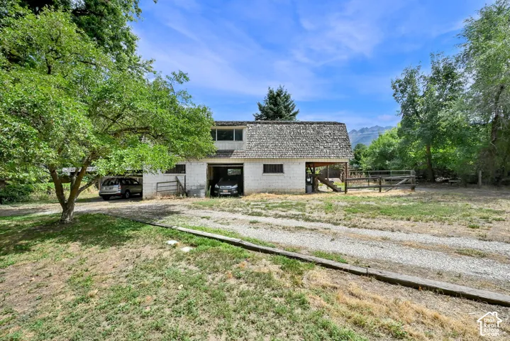 Two-story outbuilding with wood shake roofing, two open-bay garages, and a gravel driveway