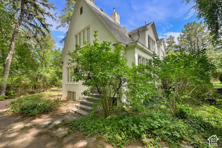 White stucco exterior with multiple windows, a steeply pitched roof, and a chimney