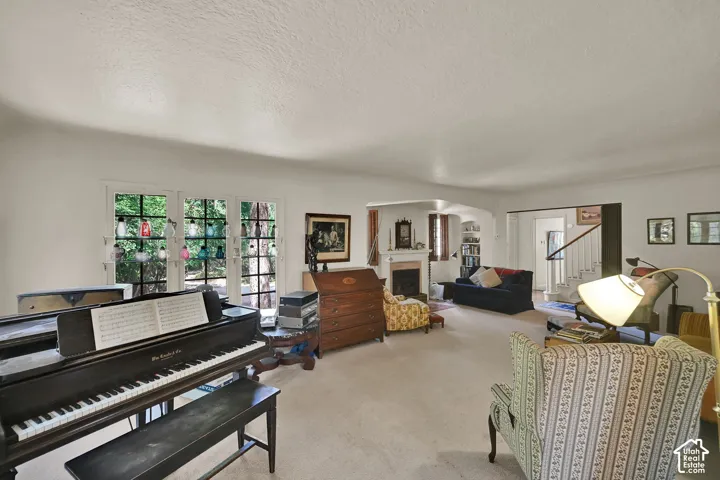 Spacious living area with carpet flooring, a fireplace, and multiple windows