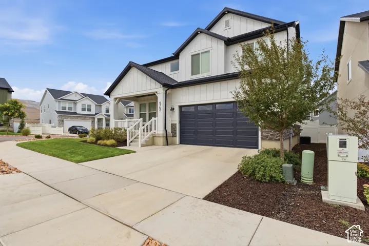 Exterior featuring board and batten siding, stone accents, covered front porch, and a two-car garage