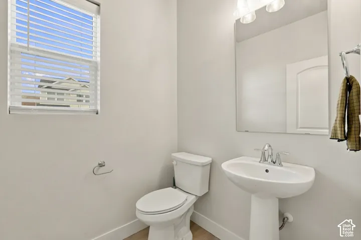 Pedestal sink with chrome fixtures and an overhead vanity light