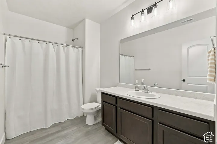 Bathroom featuring a dark wood-finish vanity, white countertop, integrated sink, and a shower with a chrome fixture