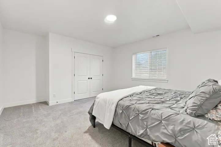 Recessed ceiling lighting, white double-panel doors, white window blinds, and light gray carpet flooring