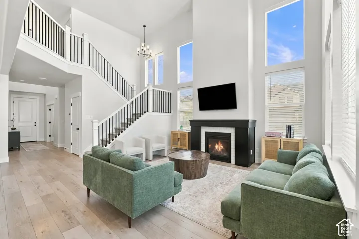 Two-story living area featuring a fireplace with a dark wood-finish mantel, wood-finish flooring, and multiple large windows