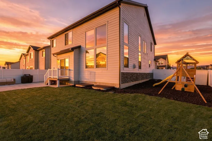 Rear exterior with white siding, stone veneer foundation, and multiple large windows