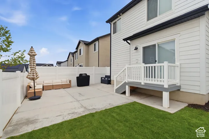 Private fenced yard featuring a concrete patio and a wooden deck with white railing