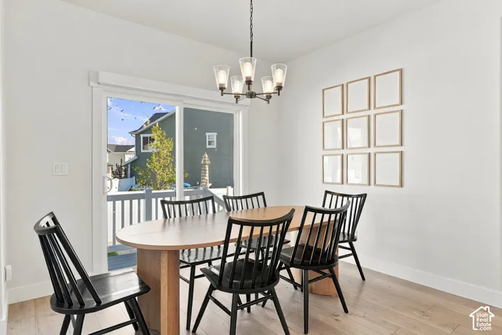 Light wood-finish flooring, a contemporary chandelier, a sliding glass door with white trim, and white painted walls