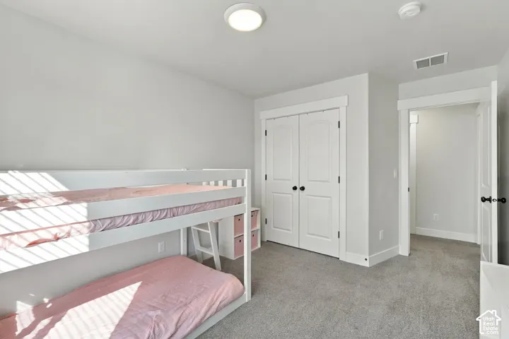 Built-in closet with double white doors, overhead lighting, and soft gray carpeting