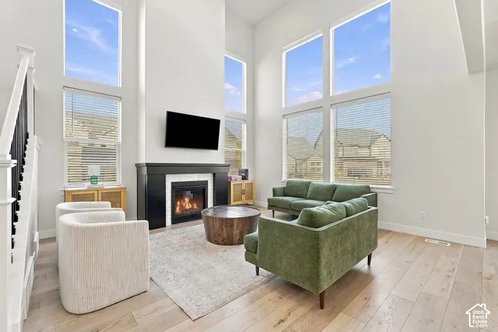 Soaring ceilings, expansive window array, wood-finish flooring, built-in fireplace, and staircase with dark balusters