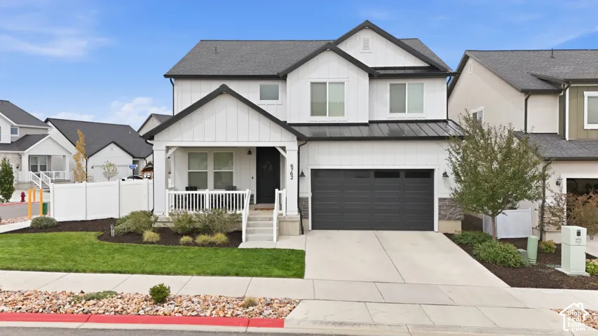 Contemporary exterior with white siding, black trim, a covered porch, a two-car garage, and a concrete driveway