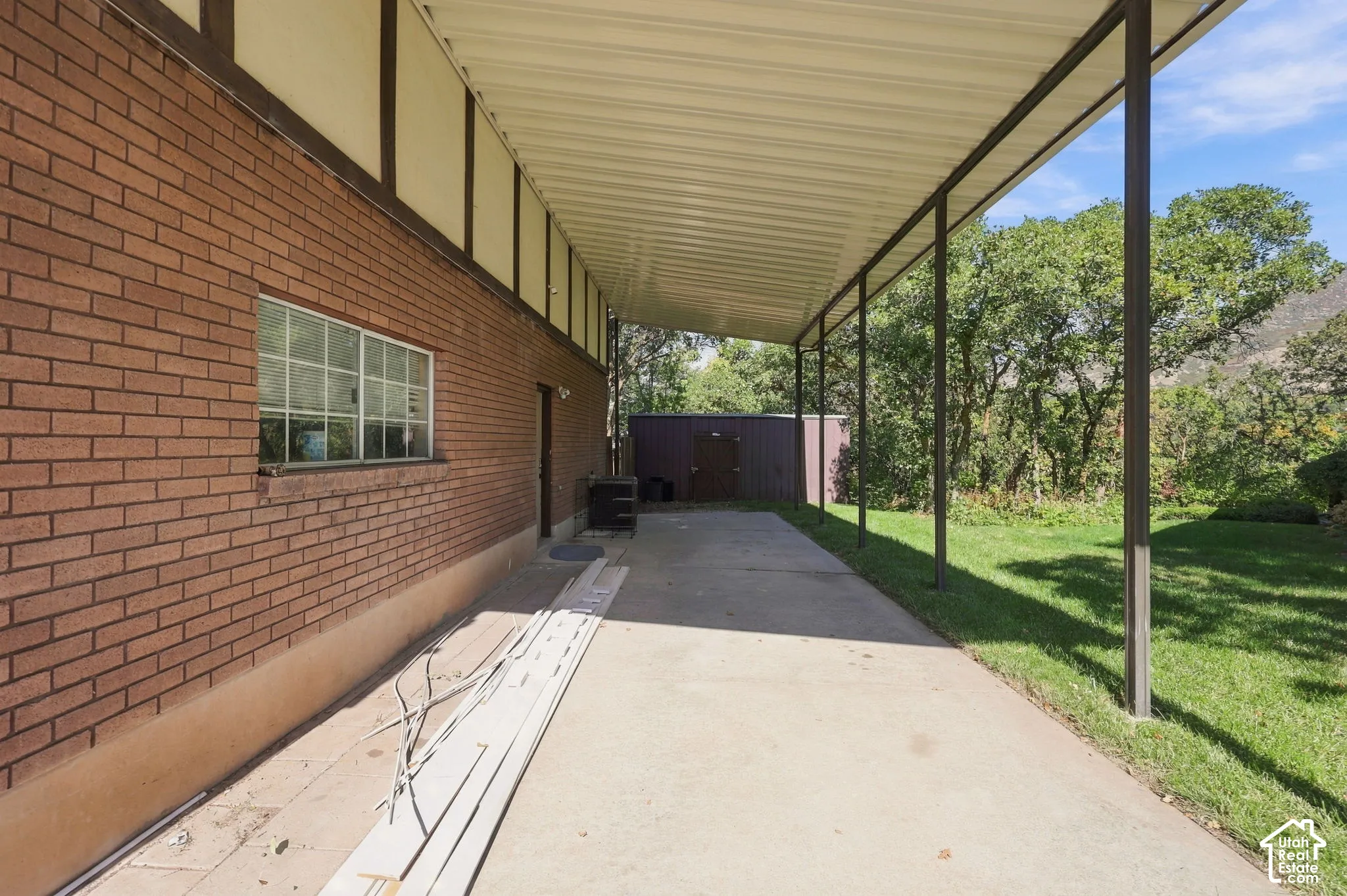 Covered RV Parking Strip  with concrete flooring, brick exterior, and a metal-framed roof