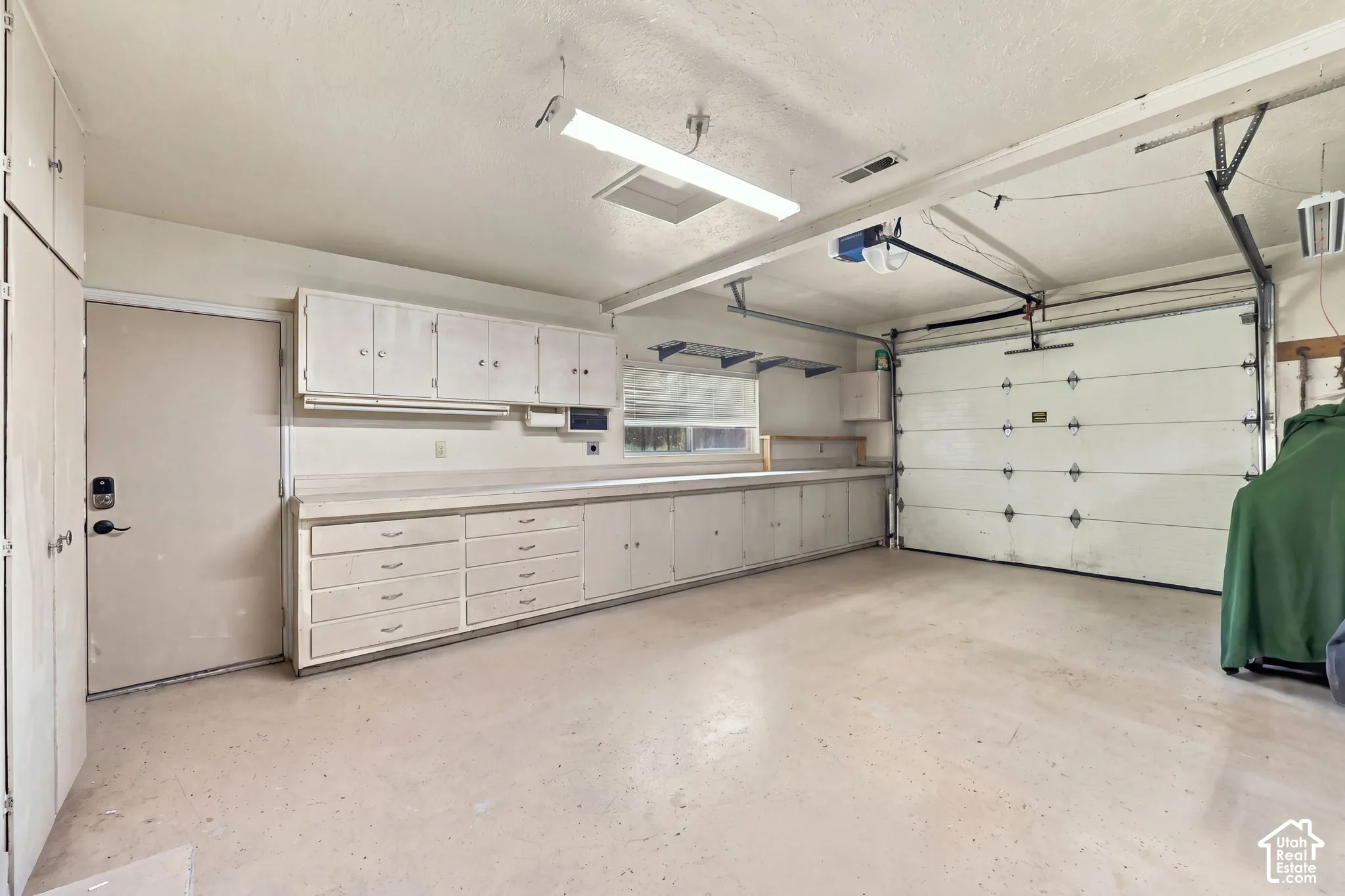 Spacious garage with extensive built-in cabinetry, workbench, and overhead storage
