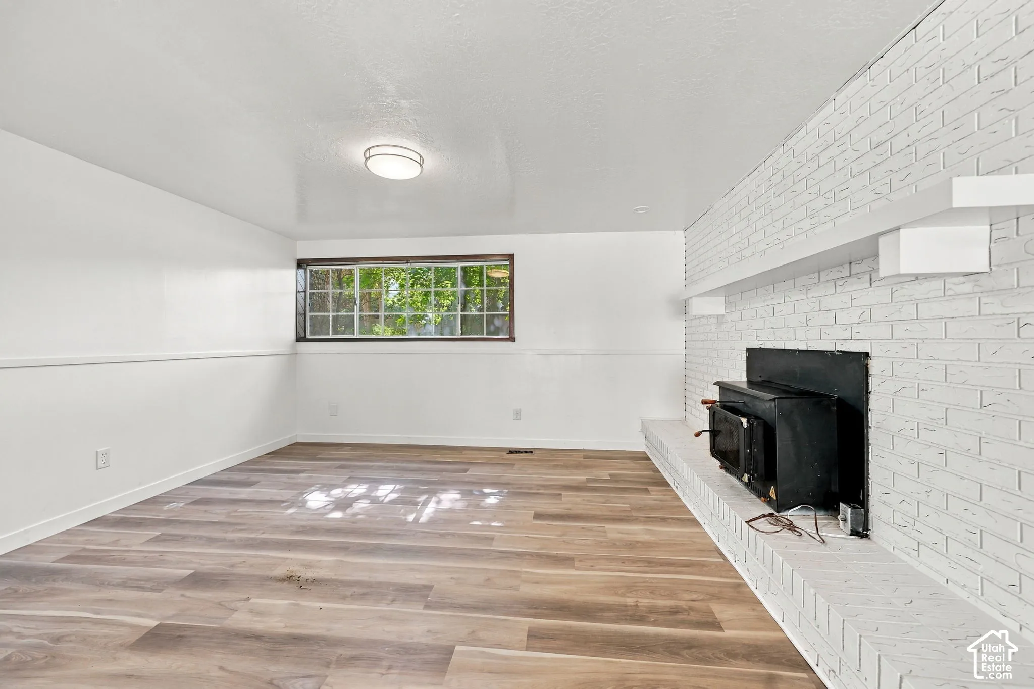 Wood-finish flooring, white painted walls, and a recessed window with grilles