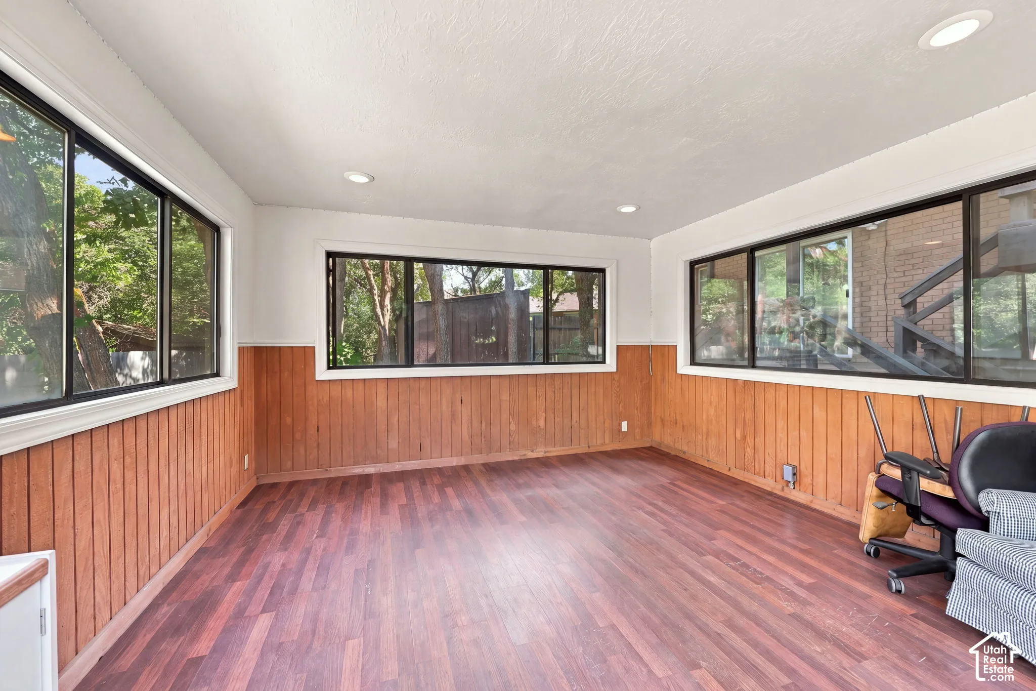 Wood-finish flooring with wood paneling and multiple windows can have multiple uses.