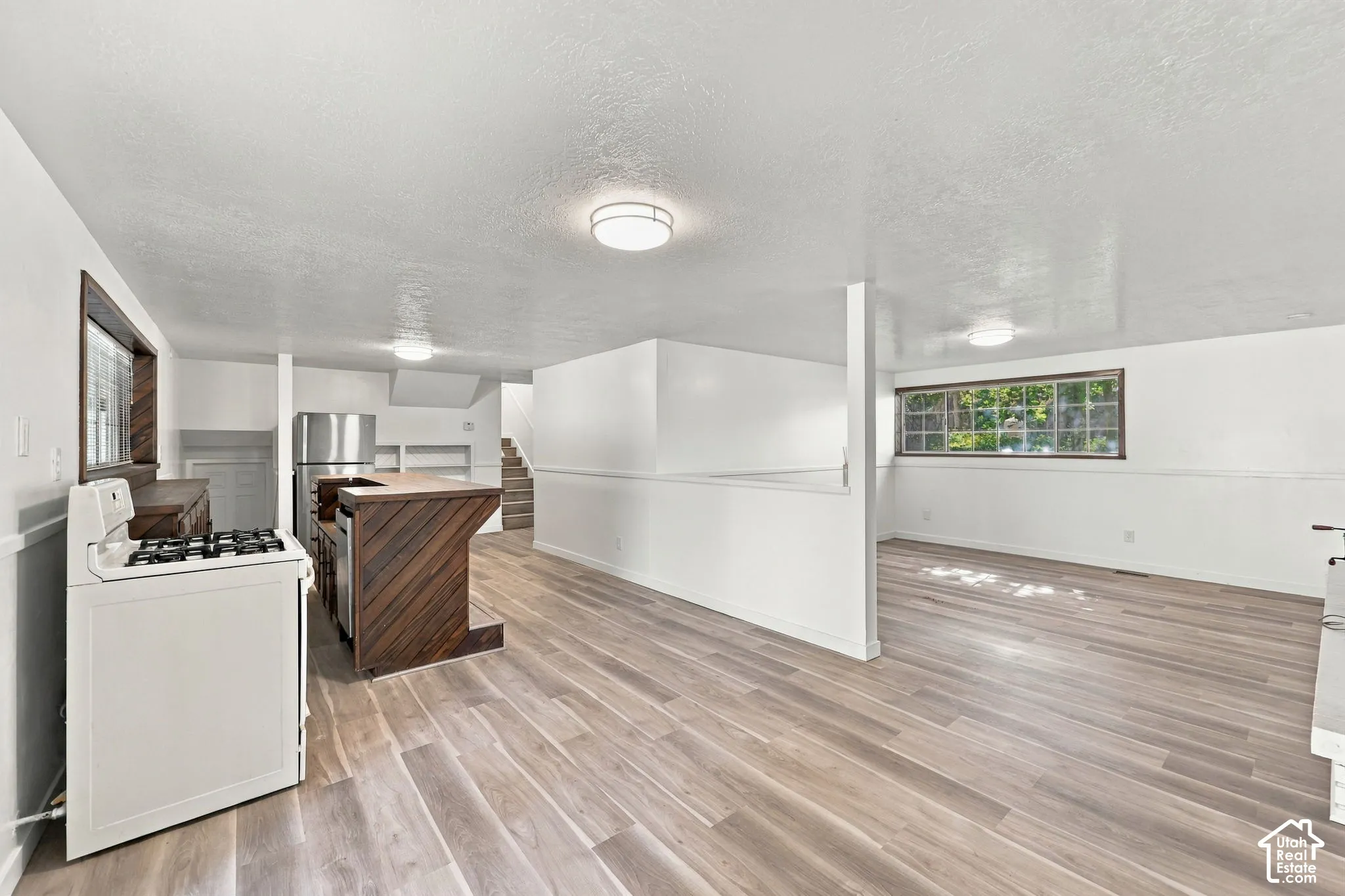 Wood-finish flooring throughout, with a built-in kitchen island, stainless steel refrigerator, and built-in shelving