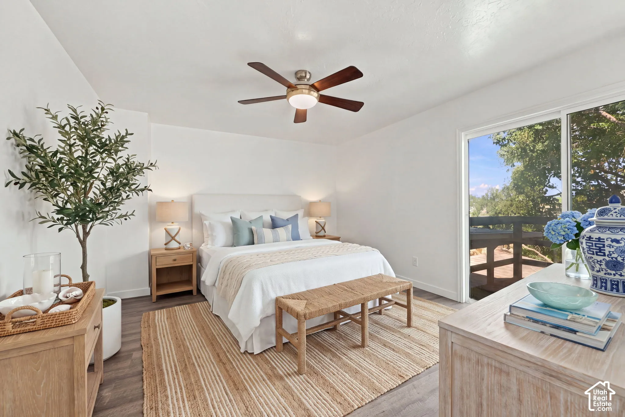 White walls featuring a ceiling fan, wood-finish flooring, and a sliding glass door