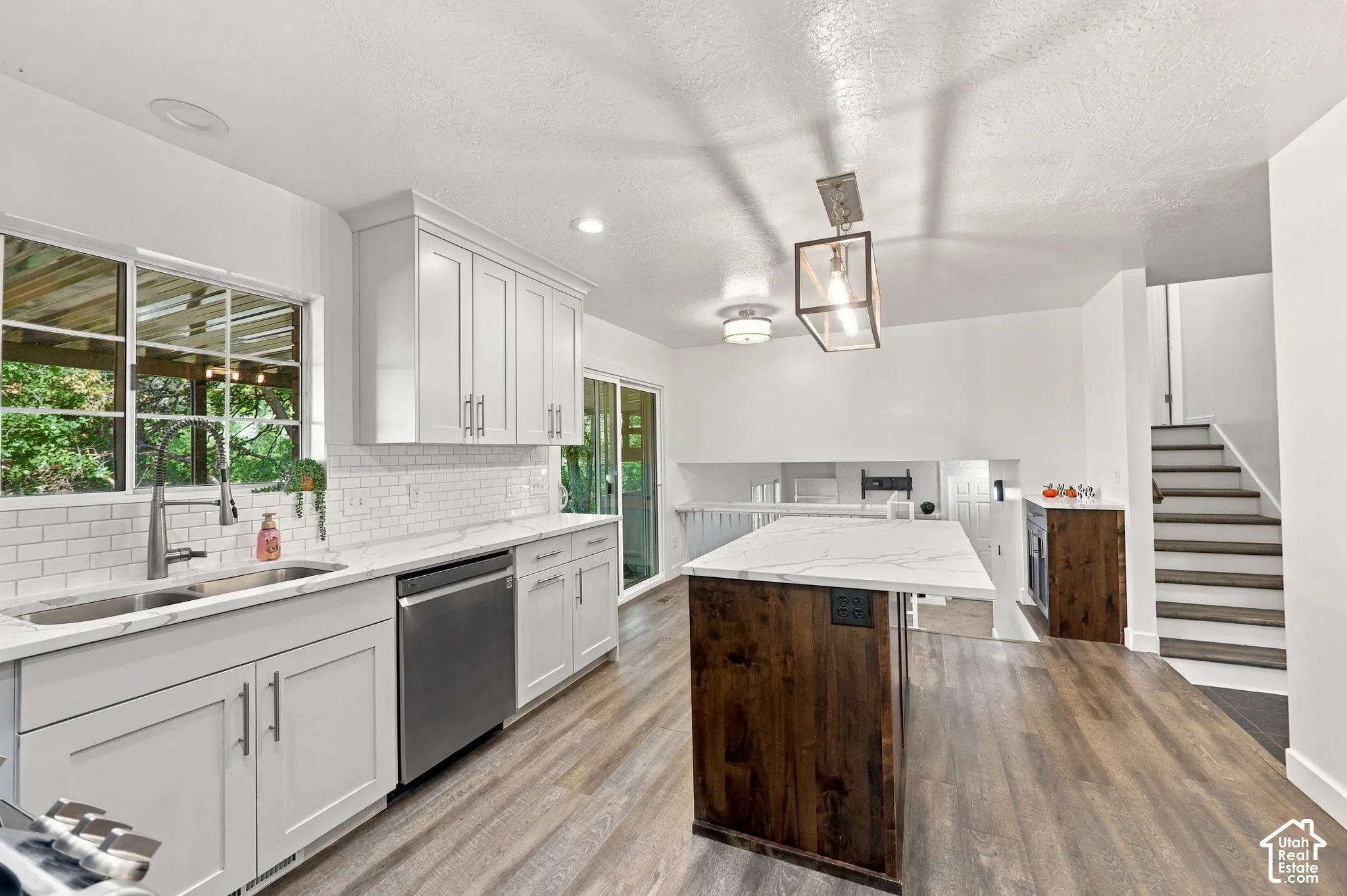 Kitchen featuring white shaker cabinetry, stainless steel sink, subway tile backsplash, and wood-finish flooring