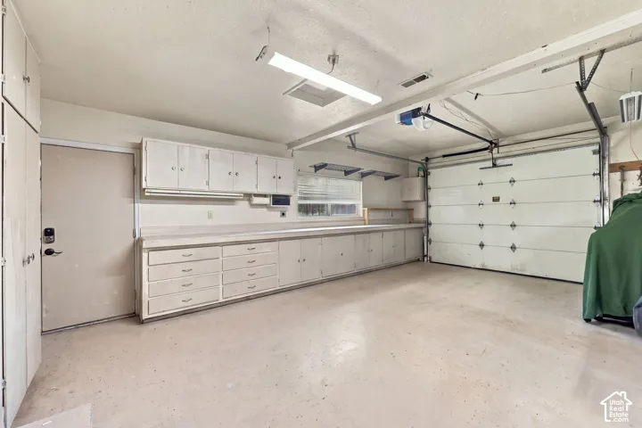 Spacious garage with extensive built-in cabinetry, workbench, and overhead storage