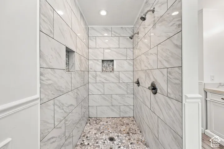 Spacious shower with large format tile, pebble shower floor, built-in shower niches, and dual shower heads