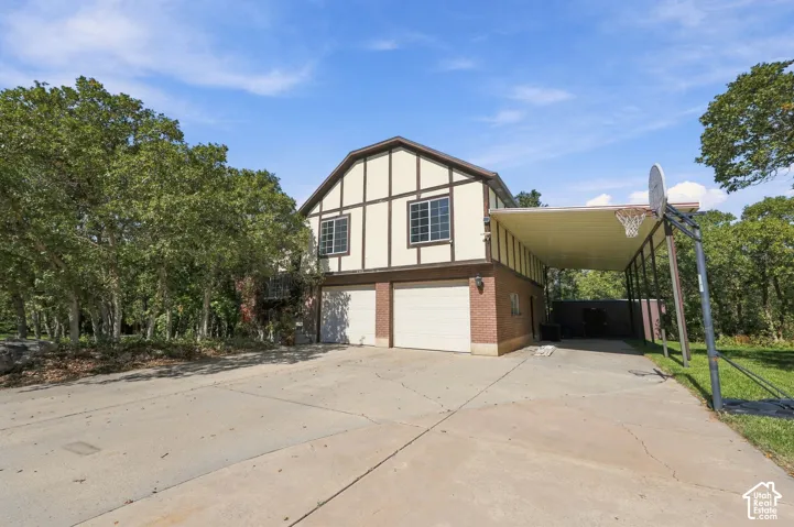 Multi-story exterior with a two-car garage, brick facade, and decorative half-timbering
