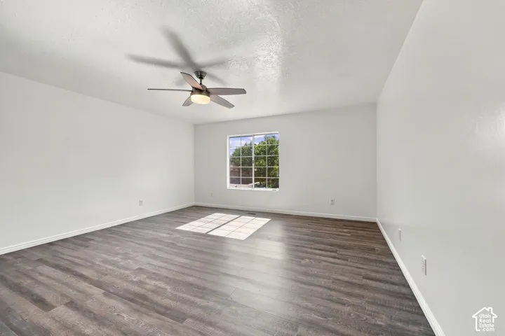 Spacious room featuring wood-finish flooring, a window with grid panes, and a ceiling fan with integrated lighting