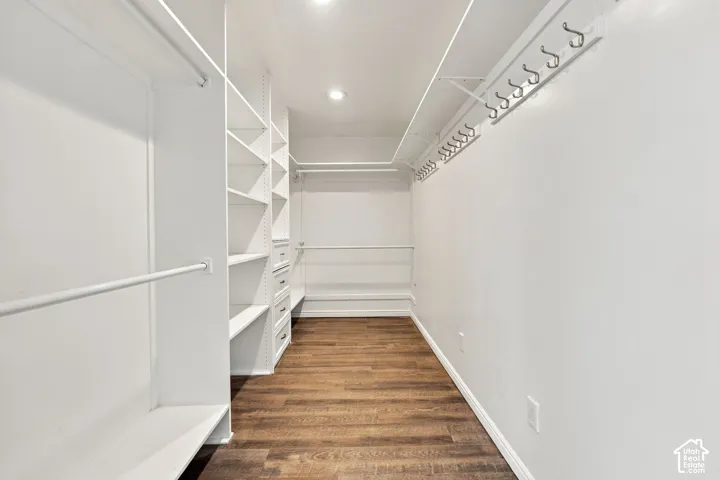 Custom closet system featuring wood-finish flooring, built-in shelving, integrated drawers, and hanging rods