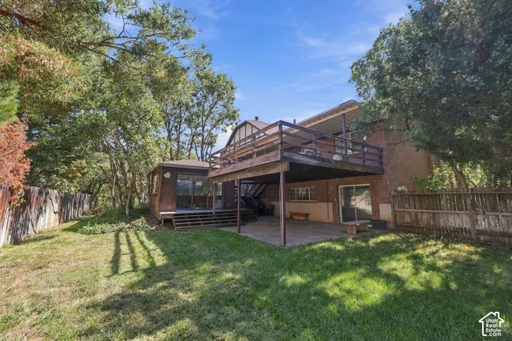 Expansive lawn with mature trees, featuring a multi-level deck and an enclosed porch
