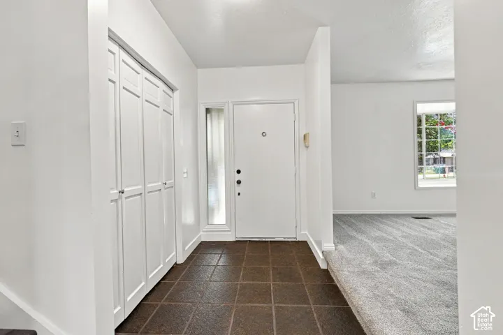 Foyer featuring square tile flooring, a side-lite entry door, and bi-fold closet doors