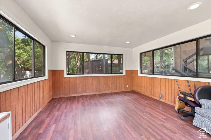 Wood-finish flooring with wood paneling and multiple windows can have multiple uses.