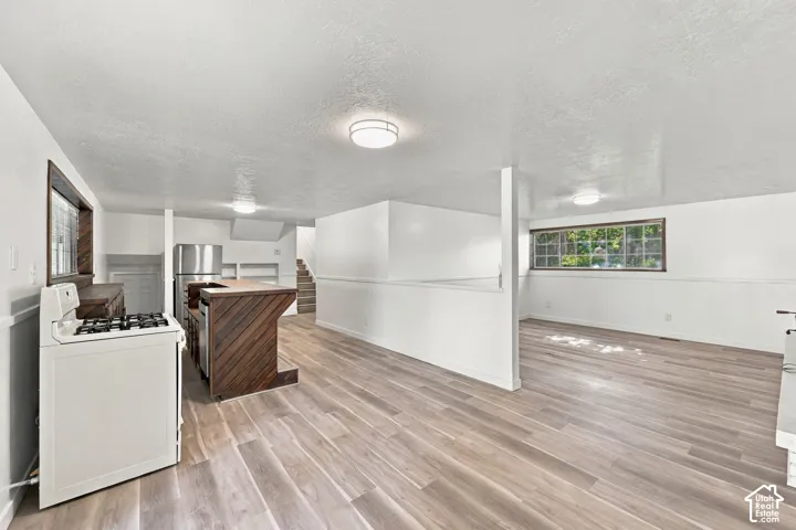 Wood-finish flooring throughout, with a built-in kitchen island, stainless steel refrigerator, and built-in shelving