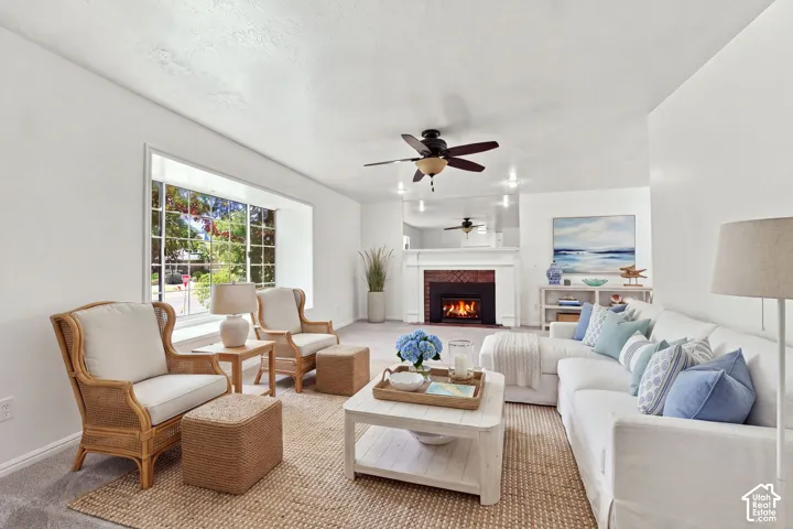 Spacious living area featuring a brick fireplace with a white mantel, ceiling fan, recessed lighting, and a large bay window