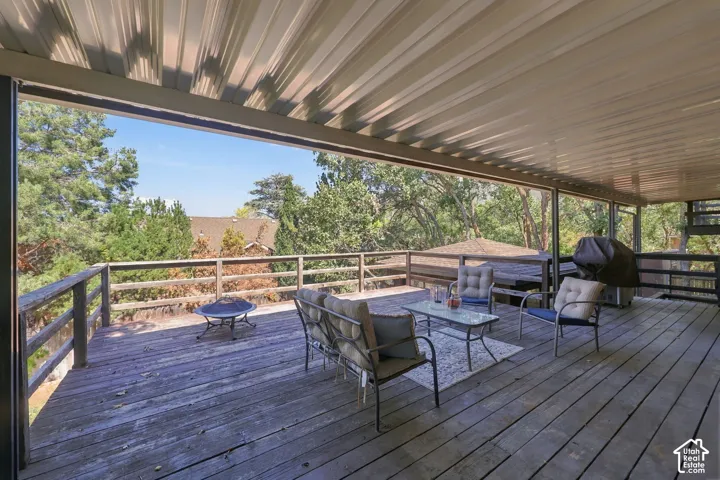 Expansive wood deck with a full-length covered patio, wood railings, and mature landscaping