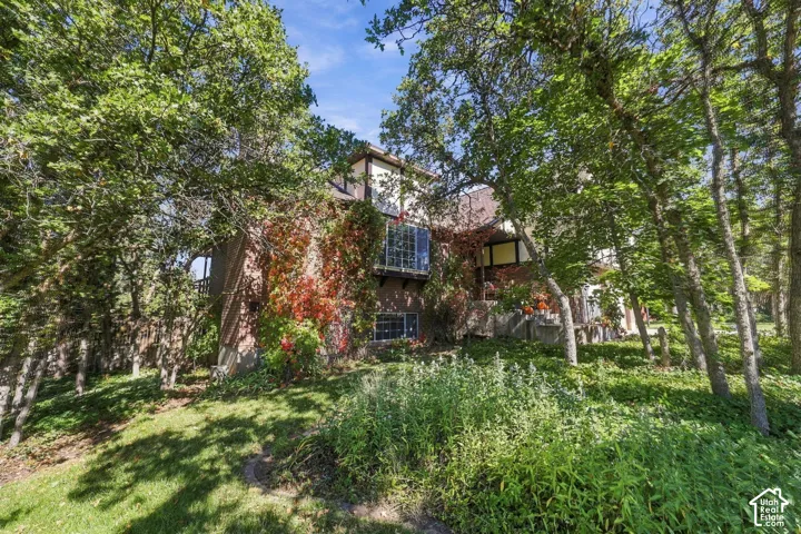 Exterior architecture featuring brick siding, a prominent bay window, and mature trees