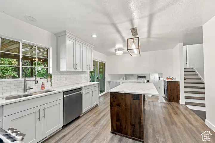Kitchen featuring white shaker cabinetry, stainless steel sink, subway tile backsplash, and wood-finish flooring