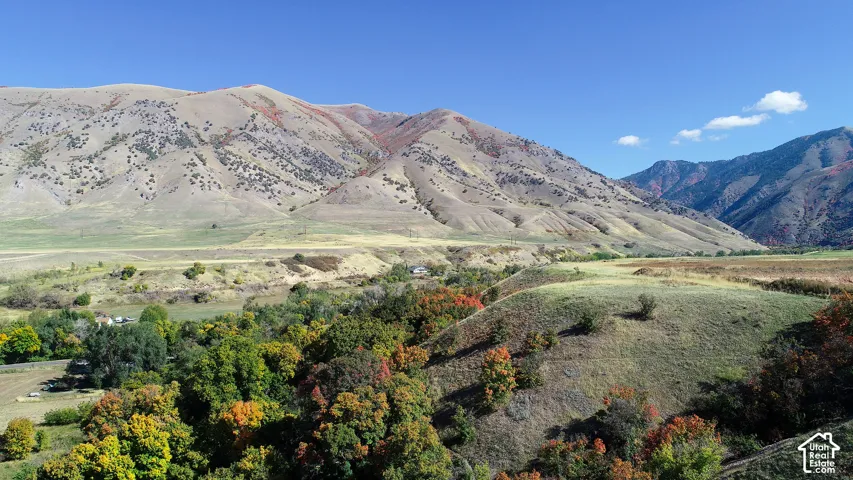Expansive natural landscape featuring varied terrain, a clear sky, and distant mountain ranges