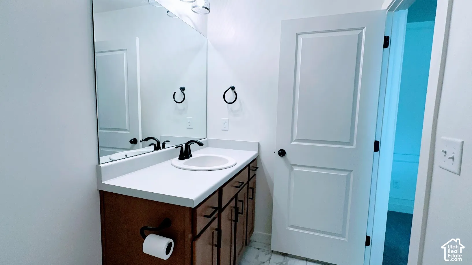 Bathroom vanity with an undermount sink, matte black faucet, and a large wall-mounted mirror