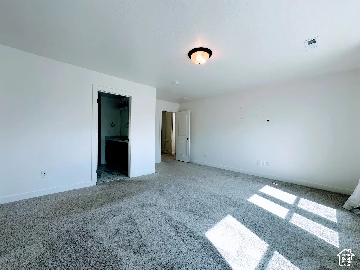 Recessed lighting, light-colored walls, and neutral carpeting