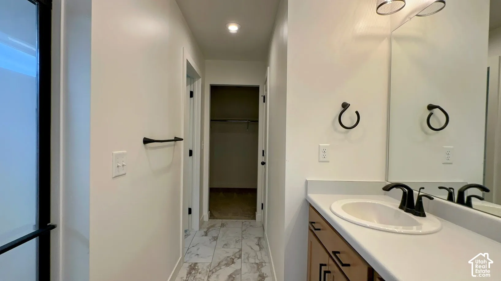 Vanity with integrated sink, black hardware, wall-mounted mirror, and overhead lighting