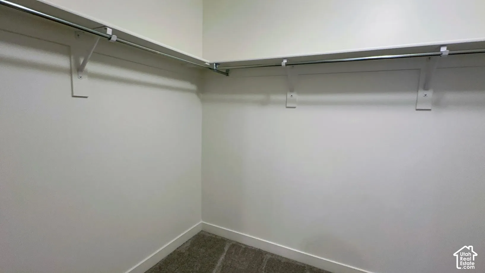 Corner closet with metal hanging rods and integrated shelving