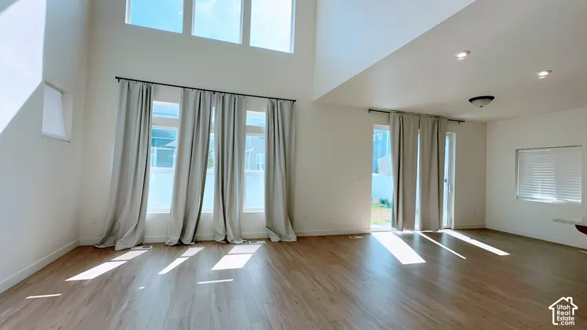 Vaulted ceilings, wood-finish flooring, recessed lighting, and multiple windows with draperies