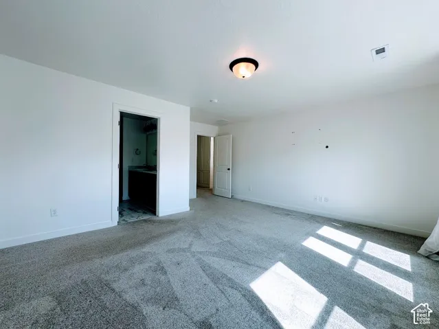 Recessed lighting, light-colored walls, and neutral carpeting