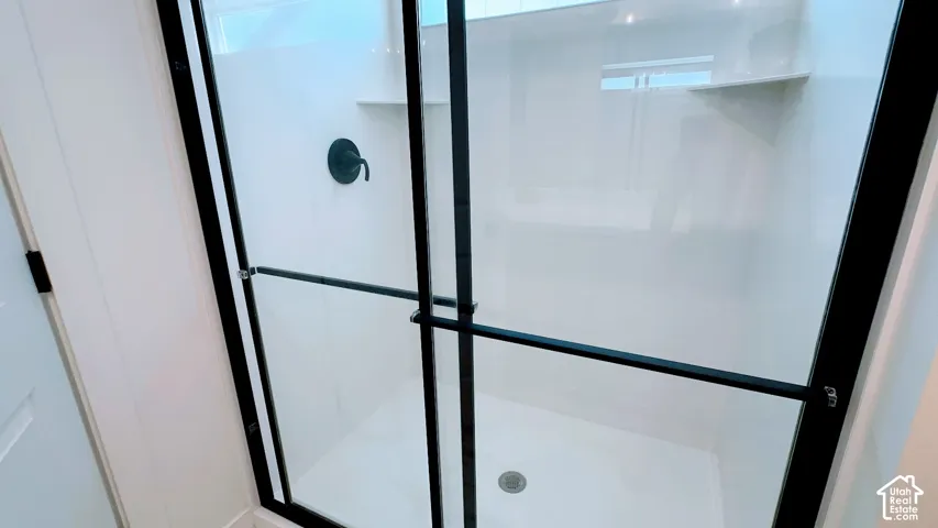 Shower enclosure with black-framed clear glass doors, integrated shelving, and a matte black shower fixture