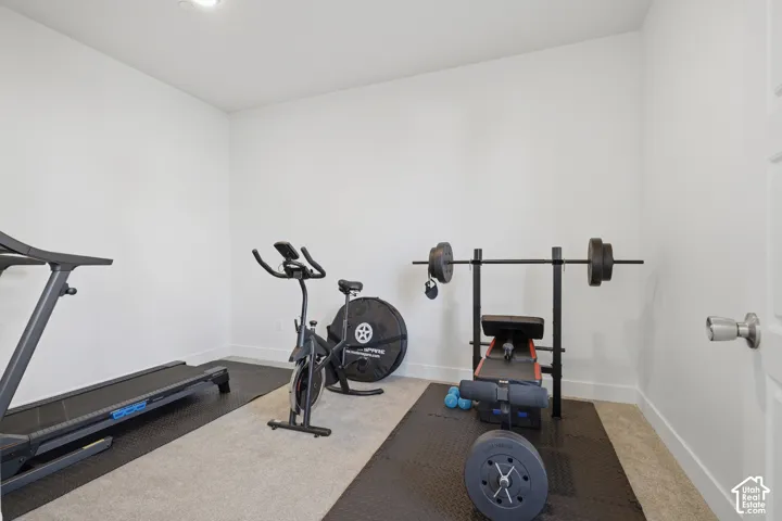 Recessed ceiling lighting illuminates a room with light-colored carpet and white walls