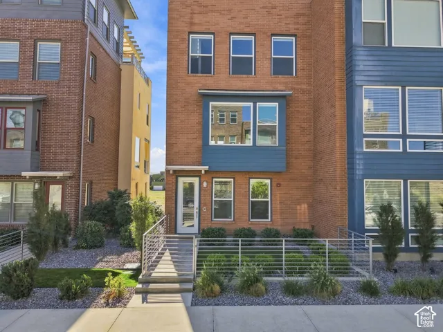 Brick facade with blue siding accent panels, multiple windows, and a glass-paneled entry door